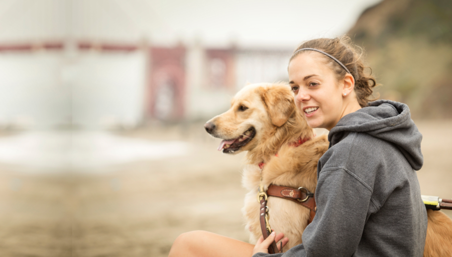 Kvinna sittandes utomhus med sin hund bredvid sig.