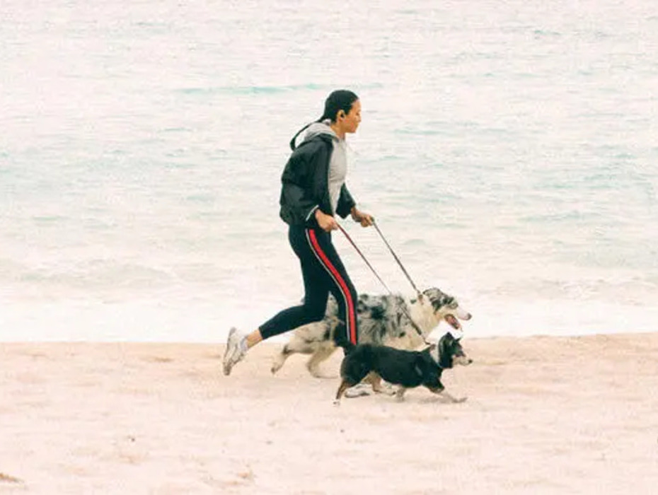 En kvinna springer längs stranden med två hundar