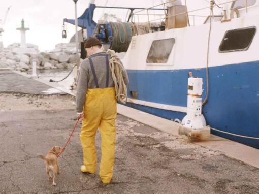 fiskare gå sin hund bredvid fiskebåt