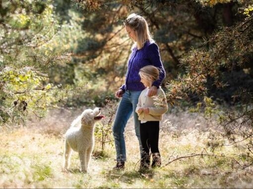 Kvinna med barn och hund i en skog
