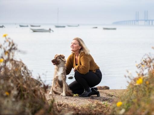 Kvinna sitter med hund vid Öresundsbron
