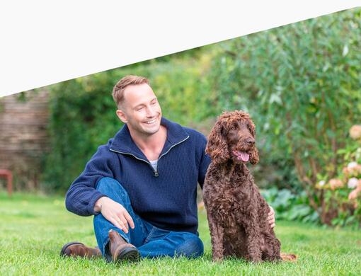 Man som sitter med sin hund på gräset